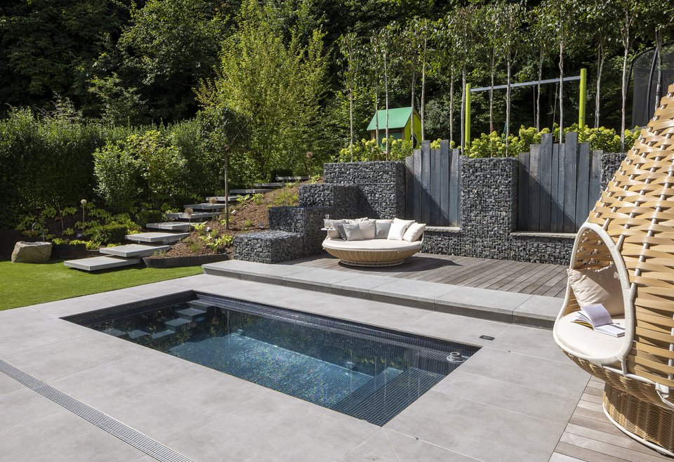 Moderner Außenbereich mit TeichMeister Mini-Pool, einer gemütlichen Sitzbank aus Korbmaterial mit Kissen und einem hängenden Korbsessel.