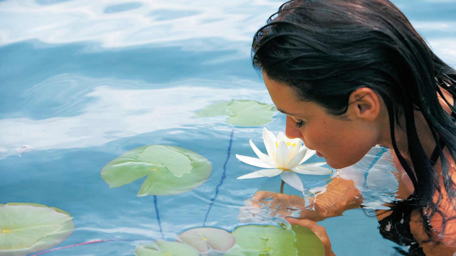 Frau rieht an Blume im Wasser