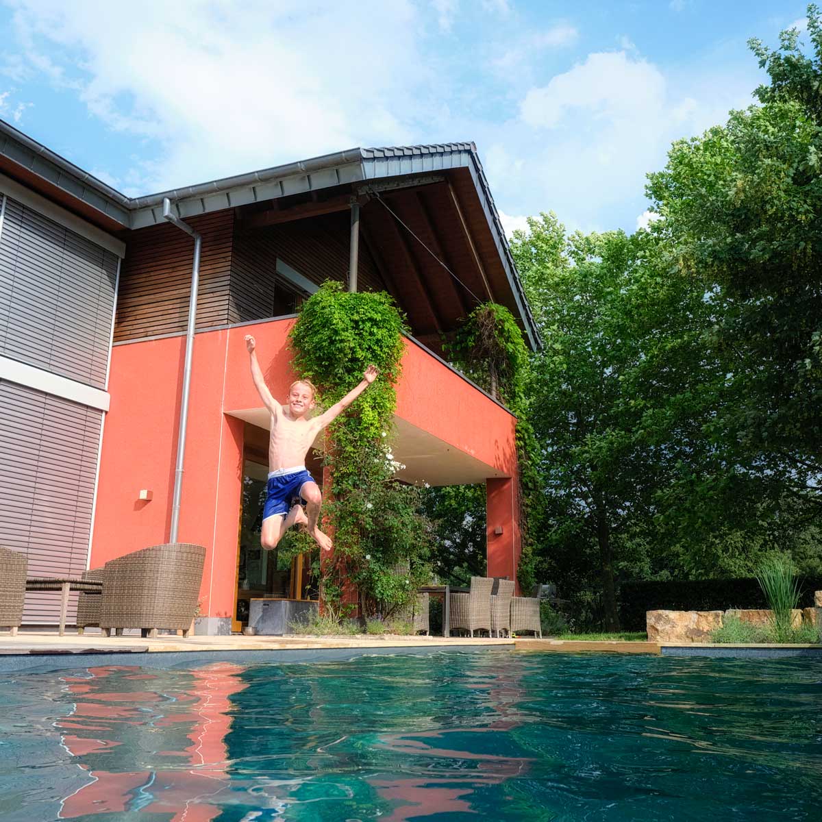 Junge springt lachend im Naturpool